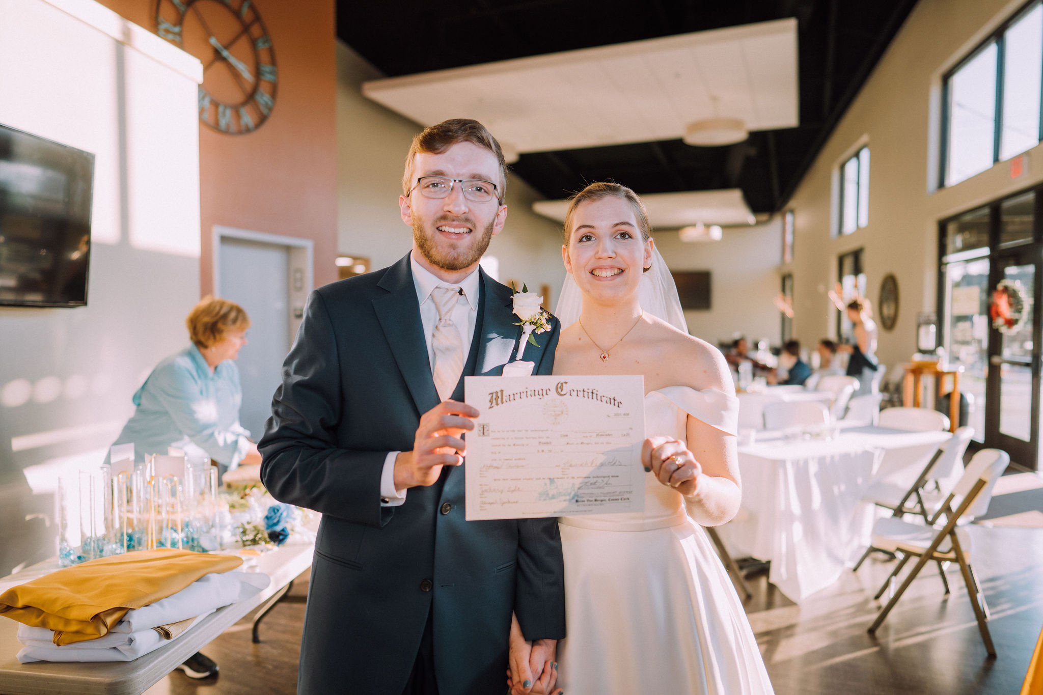 a photo of Hannah and her husband Nathaniel on their wedding day holding their certificate of marriage